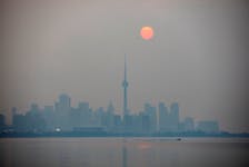 The sun rises through a cover of wildfire smoke above the CN Tower and downtown skyline in Toronto, Ontario, Canada July 20, 2021. 