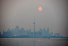 The sun rises through a cover of wildfire smoke above the CN Tower and downtown skyline in Toronto, Ontario, Canada July 20, 2021. 