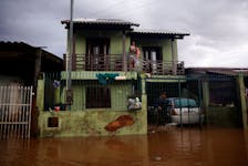 A woman pulls donated water with a sheet from the balcony of a house in a flooded area in Eldorado do Sul, Rio Grande do Sul state, Brazil May 8, 2024.