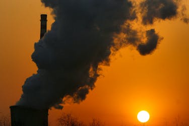The sun sets next to a smokestack from a coal-burning power station in Beijing January 9, 2008. 