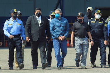 Honduras former President Juan Orlando Hernandez is escorted by authorities as he walks towards a plane of the U.S. Drug Enforcement Administration (DEA) for his extradition to the United States, to face a trial on drug trafficking and arms possession charges, at the Hernan Acosta Mejia Air Force base in Tegucigalpa, Honduras April 21, 2022.
