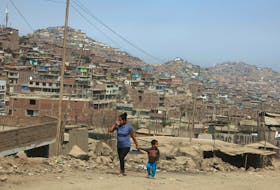 A woman and child walk on the hills  of Villa Maria del Triunfo, a shanty town on the outskirts of Lima, Peru May 9, 2017. Picture taken May 9, 2017.