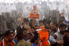 A supporter of the Bharatiya Janata Party (BJP) holds up a cut-out of India's Prime Minister Narendra Modi during his election campaign rally, in New Delhi, India, May 22, 2024.