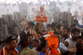 A supporter of the Bharatiya Janata Party (BJP) holds up a cut-out of India's Prime Minister Narendra Modi during his election campaign rally, in New Delhi, India, May 22, 2024.