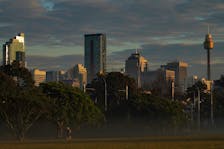 Runners jog through a park in front of the city skyline at sunrise in Sydney, Australia, August 28, 2022.