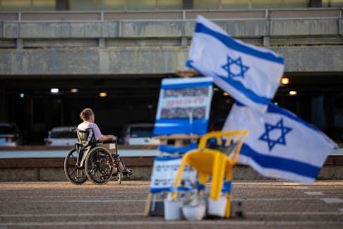 A man in a wheelchair passes near Israeli flags and pictures of hostages kidnapped during the deadly October 7 attack by the Palestinian Islamist group Hamas from Gaza, in Tel Aviv, Israel, May 31, 2024.