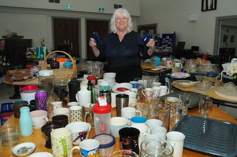 Parishioner Doris Squires shows a pair of blue mugs at her assigned table at the Anglican Church of the Good Samaritan fundraiser garage sale for Guatemala on June 1.
-Photo by Joe Gibbons/The Telegram