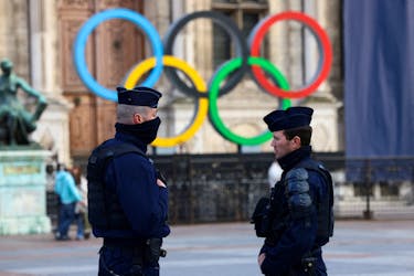 French police officers stand guard near the Olympic rings which are displayed for the Paris 2024 Summer Games in Paris, France, March 21, 2023. REUTER/Yves Herman/File Photo