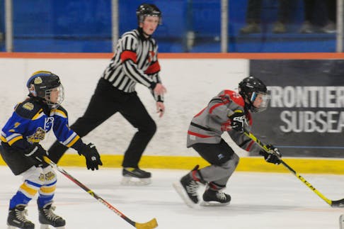 As the game referee keeps a close eye on the play, Jace March, right, of the Bay Arena Rovers, heads down ice with the puck as Anna Bazeley, 2, left, of the Avalon Celtics, follows behind in third-period action of their game in the 2024 Exile Under-9 novice invitational hockey tournament at the D.F. Barnes Arena on Saturday afternoon won 6-1 by the Rovers.
-Photo by Joe Gibbons/The Telegram