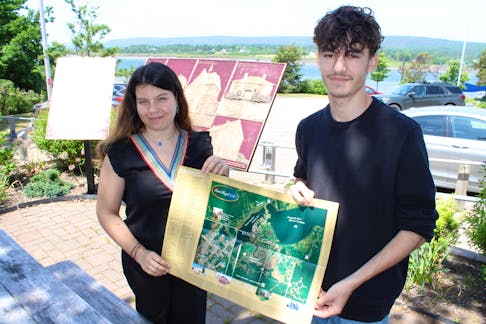 Elisa Livertout and Charles Melsheim-Orsatti, tourism interns from Royan, France, hold a map of Port Royal from 1710 that has been superimposed on a modern map of Annapolis Royal.  
Jason Malloy