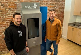 Corey Yantha stands with Dr. Mark Tyndall next to the pilot machine that went in next to a safe injection site in Vancouver. It will soon be dispensing clean opiates to addicted patients.