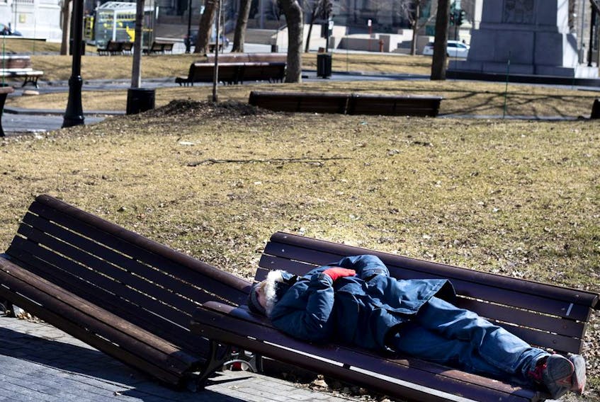 A homeless man sleeps on a bench in Dorchester Square as Montreal deals with the coronavirus crisis March 27, 2020.  