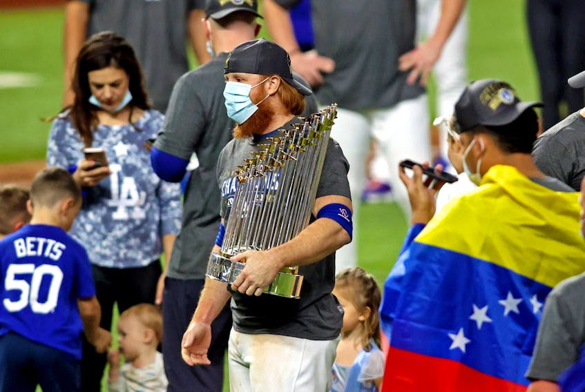 Justin Turner (centre) celebrates with the trophy after the L.A. Dodgers beat the Tampa Bay Rays to win the World Series on Tuesday night. Turner had received a positive COVID test earlier in the game and had been ordered off the field. 