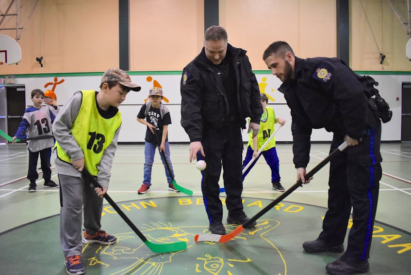 Constable Dwight Miller, middle, conducts a faceoff between Justin Ward, left, and Constable Liam MacKinnon as part of the Cape Breton Regional Police Boys and Girls Club weekly floor hockey program at the John Bernard Croak VC Memorial School gym in Glace Bay. The program began in 1972 and continues today in East Division.