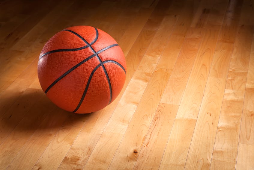 A basketball sits on a hardwood basketball court.