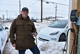 Mike Kenny, owner of the AllEV car dealership in Charlottetown, holds a charge cable attached to a Level 2 charger outside the dealership. By the end of the year, Maritime Electric says it will install 50 stations like it across the province.