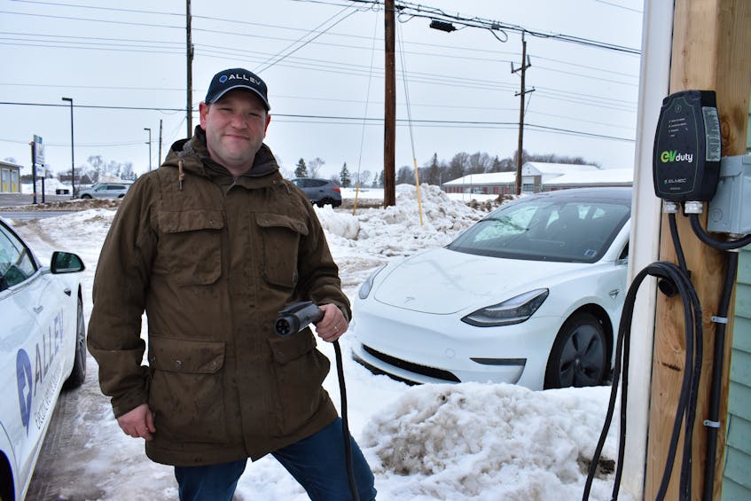 Mike Kenny, owner of the AllEV car dealership in Charlottetown, holds a charge cable attached to a Level 2 charger outside the dealership. By the end of the year, Maritime Electric says it will install 50 stations like it across the province.