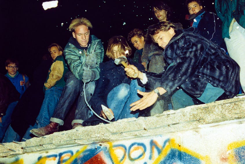  West-Berliners break the Berlin Wall with hammers and crosses.