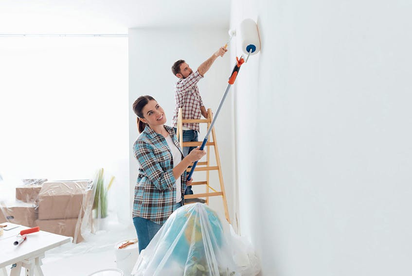 Home makeover and renovation: young happy couple painting their new house interiors using paint rollers