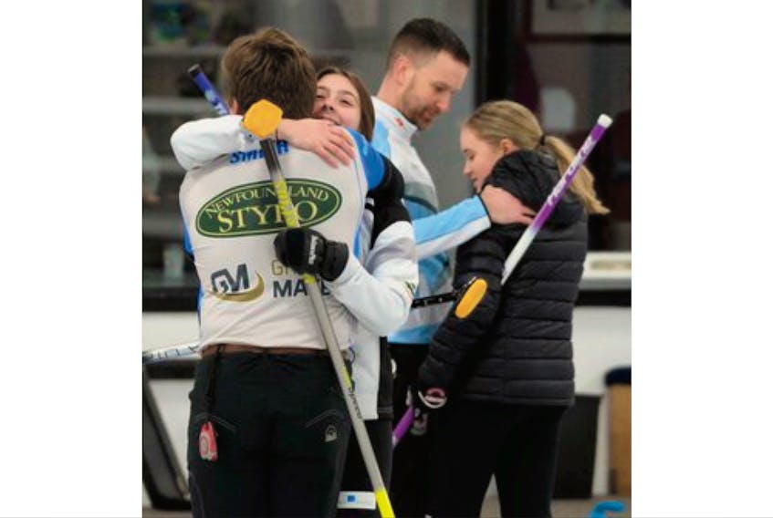 Greg Smith and Mackenzie Mitchell hug after winning the provincial mixed doubles curling championship Sunday afternoon by defeating the team of Brad and Hayley Gushue (background) in the final of the event at the Re/Max Centre in St. John’s — Keith Gosse/The Telegram
