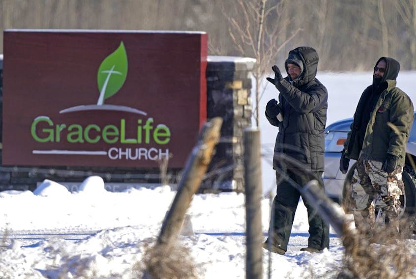 Two men keep unwelcome visitors from entering the property at  GraceLife Church in Parkland County, just east of Edmonton, on Sunday February 7, 2021. The church has defied government pandemic restrictions multiple times and held a church service on this day.