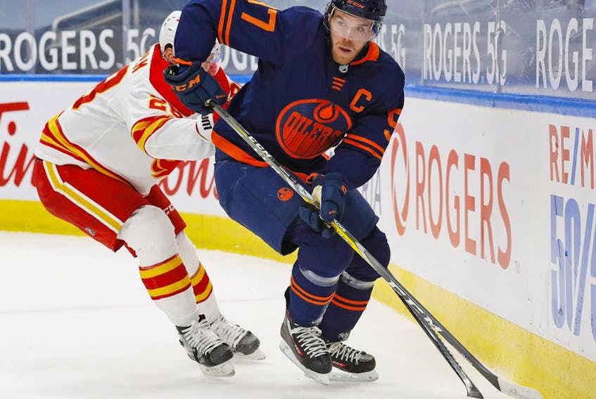  Edmonton Oilers forward Connor McDavid (97) moves the puck past Calgary Flames forward Elias Lindholm (28) during the first period at Rogers Place on Feb. 20, 2021.