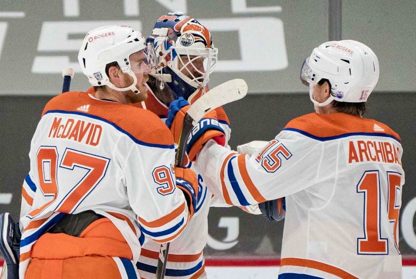 Edmonton Oilers forward Connor McDavid (97) and goalie Mike Smith (41) and forward  Josh Archibald (15) celebrate their victory against the Vancouver Canucks at Rogers Arena on Feb. 25, 2021. 
