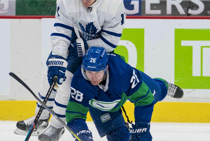 Canucks forward Antoine Roussel (26) checks Toronto Maple Leafs forward  Zach Hyman (11) in the first period at Rogers Arena on Saturday night. 
