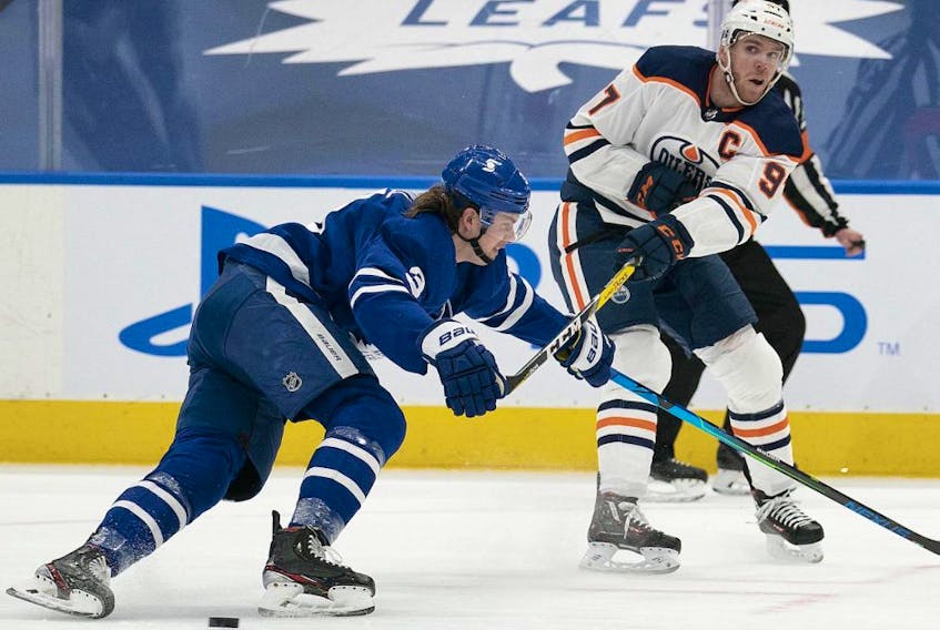 Edmonton Oilers center Connor McDavid (97) moves the puck against Toronto Maple Leafs defenseman Justin Holl (3) during the second period at Scotiabank Arena on March 27, 2021. 