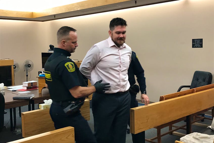 Justin Jennings, 34, is escorted from a provincial courtroom in St. John's Monday by a sheriff’s officer after appearing on home invasion and weapons charges. Jennings' new lawyer, Averill Baker, is asking the Crown to withdraw all the charges, saying there are no credible witnesses in the case.
