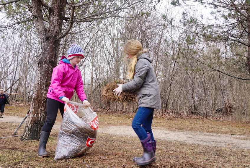 Abigail Smith and Brooke Dickie participate in a cleanup of the Trestle Trail in Liverpool April 19.