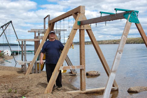 Steve Harris, owner of Mary March Wilderness Park, shows the current water level of Red Indian Lake as he stood next to a swing set along the beach Thursday, June 7.