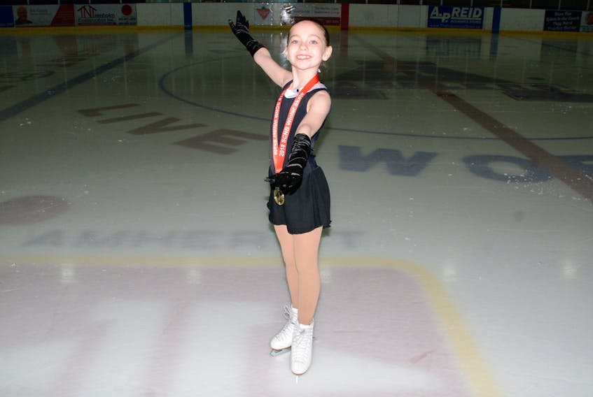 Rachel MacDiarmid, a member of the Amherst Skating Club, poses with her medal at Amherst Stadium Wednesday night.