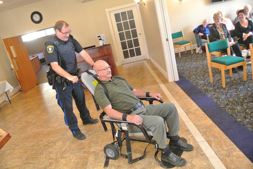 There were a few chuckles and an air of delight at the Seniors Safety Academy as Const. Tom Wood with the Amherst Police confined Senior Safety Coordinator Ray Bristol to a restraint chair for a demonstration. Amherst Police recently received the chair, which has become increasingly necessary Wood said when dealing with incidents of drug and alcohol-related aggression. 
Christopher Gooding/Amherst News