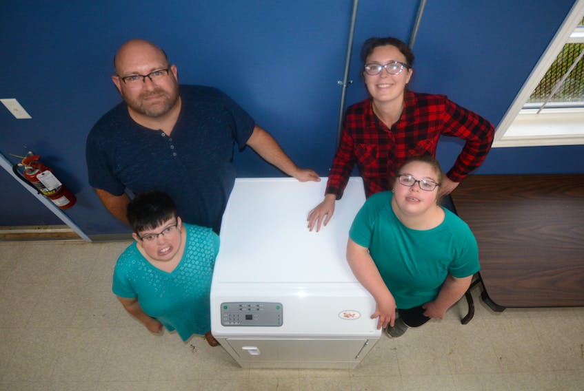 The GOVRC is ready to wash your laundry. Standing alongside the industrial dryer is: (clockwise, from top left) Paul Williams, executive director at the GOVRC, and clients Lauren Davis, Tylor Tennant, and Charlene Smith.