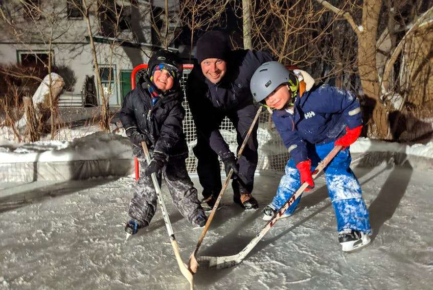 Five-year-old Eddie Olscamp, left, dad Elliot and seven-year-old Henry out on the backyard ice rink for the first time.