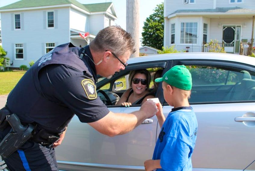 Const. Tim Hunter of the Amherst Police Department and cadet Jayden Dowe check out the licence of ‘motorist’ Nathalie Chevarie during a Cops for Kids checkpoint in front of the Amherst Stadium. 