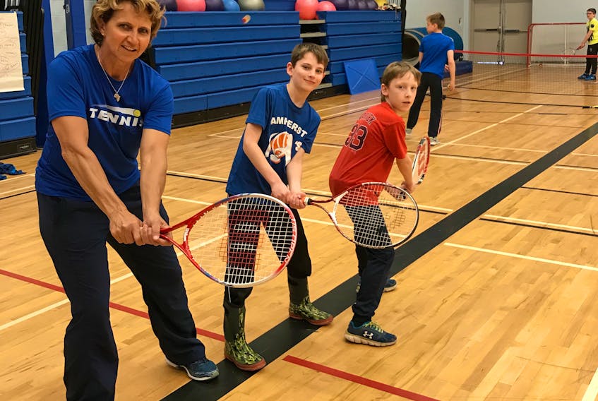 Tennis Nova Scotia technical director Marijke Nel works with Spring Street Academy Grade 5 students Tyler Quilty and Kooper Purnell during an introduction to tennis session on Wednesday. Tennis Nova Scotia and Amherst are joining forces on June 2 for a series of events at the Lions Park tennis courts.