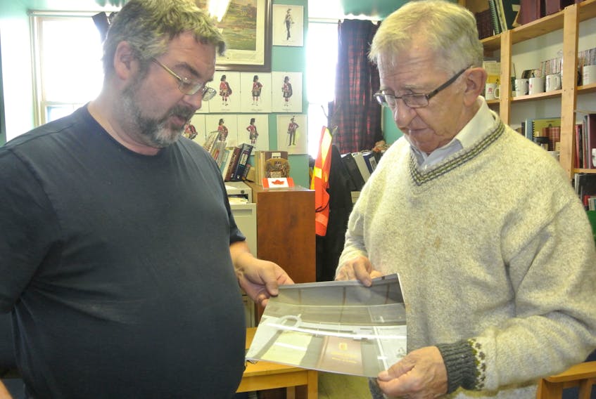 North Nova Scotia Highlanders assistant curator John Wales, left, and curator Ray Coulson look over a photograph of the key to Amherst that’s in a Russian museum. The key was given to the Atlantic consul to the Soviet Union during a 1943 visit to Amherst to tour war industries in the community. It was photographed in Central Armed Forces Museum in Moscow eight years ago.