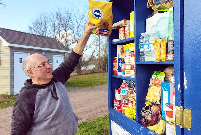 Kim Campbell checks out a Pay it Forward Pantry on Elmwood Drive in Amherst. The pantry was put in place late last week by a group of volunteers and came from a Make It Happen gathering last year where people were asked to come with ideas how to make Amherst a better community.
