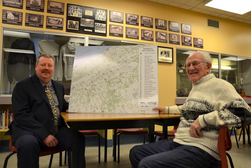 Middleton Region High School principal Jim Gushue, left, and former principal Al Peppard hold up a map that pinpoints each of the 27 feeder schools that sent their high school students on to the big new school in Middleton when it opened in 1949.