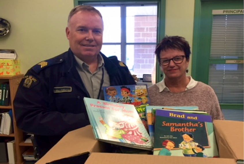 Staff-Sgt. Dan MacGillivray presents books to Champlain Elementary School Principal Lynn Winter for the Annapolis District RCMP’s Adopt-A-Library Program.