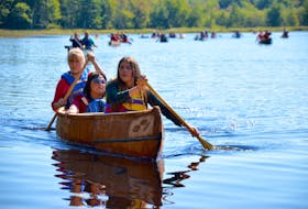 Cedar Meuse-Waterman, left, Chief Carol Dee Potter, and Karlee Peck paddled this new birch bark canoe from Jake’s Landing to Kedge Beach Sept. 15. Cedar and Karlee helped Todd Labrador build the canoe at Keji over the summer.