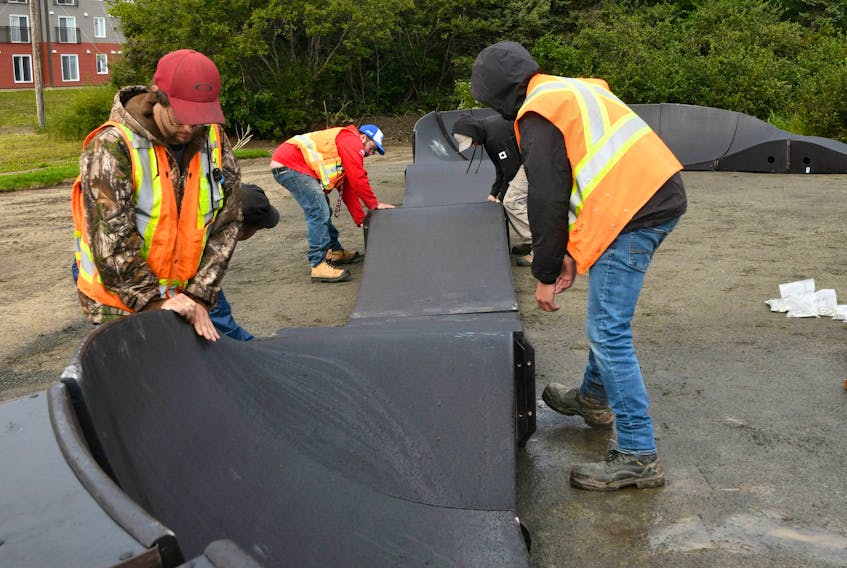 Workers from Labrador City recreation department assist Graham Cooke of Canadian Ramp Company with the assembly of the pump track.