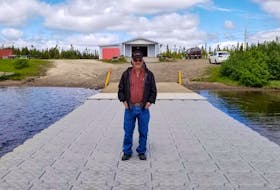 Harold Clarke dockside in front of boathouse at Jean Lake, Wabush.