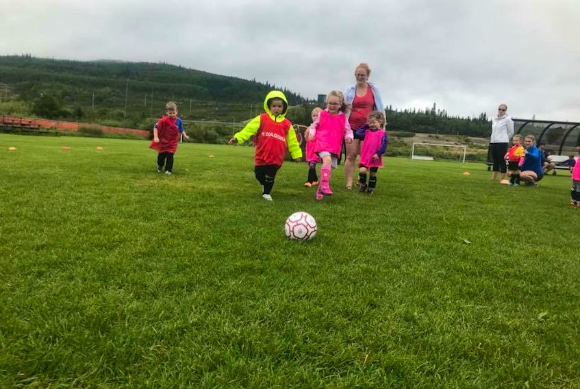 Kids enjoying kicking the ball around on the soccer pitch.