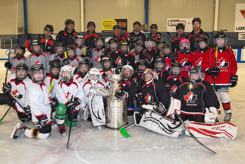 These hockey skills camp participants and officials proudly pose with the Iconic Stanley Cup.