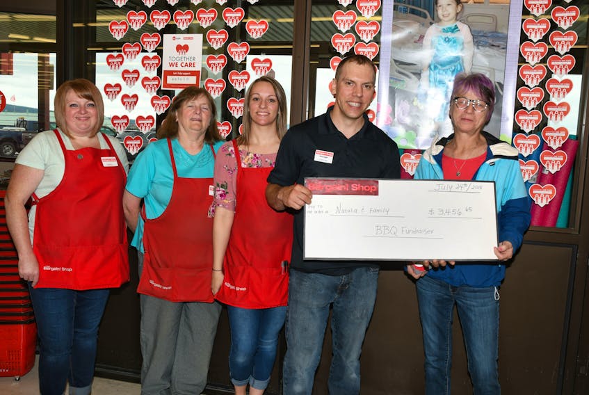Bargain Shop employees and manager, Dwayne Brown, present a cheque to Natalie Janes, Natalia Williams' grandmother, to help with Natalia's expenses for leukemia treatment.