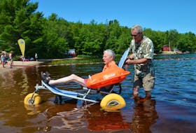 Tom Faulkner, who has used a wheelchair most of his life, rolls into the water at Raven Haven with a little guidance from Michael Gunn. The Mobi-Chair floats, allowing people with mobility issues the opportunity to participate in recreational activities. The chair is kept at Raven Haven and people can call to reserve its use. LAWRENCE POWELL