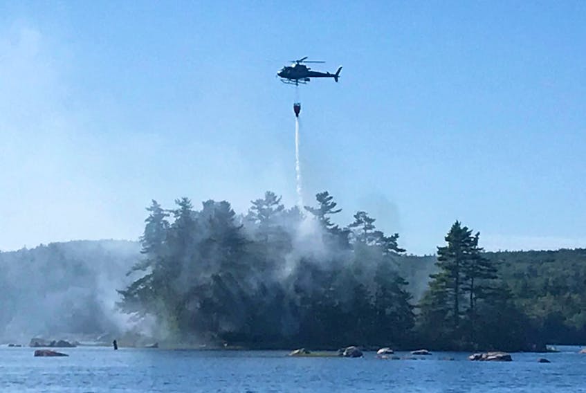 A Lands and Forestry helicopter pilot drops a load of water on a fire burning on a remote island in Kings County Aug. 28. After arriving via boat, firefighters launched a ground attack to tackle the remaining flames. - JENNIFER DANIELS PHOTO